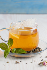 A glass cup of green natural tea with ginger, lemon, mint and honey on wooden rustic background. Healthy drink.