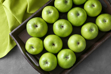 Tray with fresh green apples on grey background