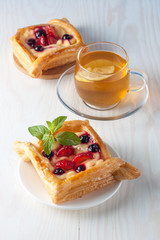Fresh fruit tart with berries jam decorated with cranberry, mint on wooden rustic background wit a cup of tea. Desert. Morning healthy breakfast and evening dinner.