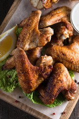 Close-up photo of bbq chicken wings with fries and beer. Barbeques meat with sauces, ketchup, mayonnaise. Fast and junk food concept. 