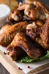 Close-up photo of bbq chicken wings with fries and beer. Barbeques meat with sauces, ketchup, mayonnaise. Fast and junk food concept. 