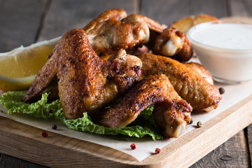 Close-up photo of bbq chicken wings with fries and beer. Barbeques meat with sauces, ketchup, mayonnaise. Fast and junk food concept. 