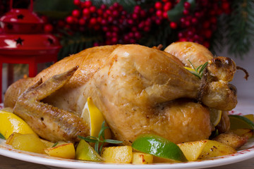 Whole roasted chicken or turkey with potatoes, lemons and limes on Christmas and New Year background, horizontal
