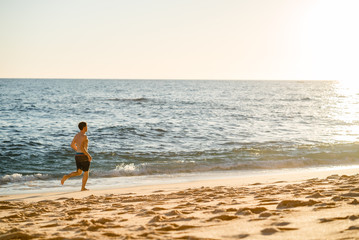 Man running on the beach at sunset