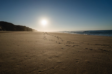 Footsteps on the beach in Portugal at sunset