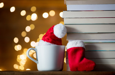 Obraz na płótnie Canvas white cup with Christmas hat and books