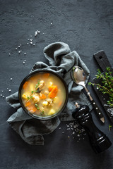 Fresh fish soup in bowl on dark background, top view