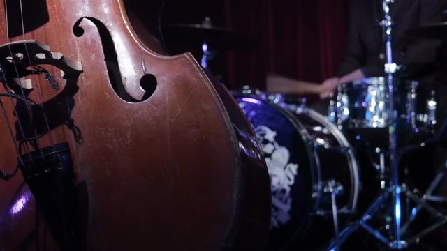 Drumm kit and contrabass jazz musical instruments. Musicians playing contrabass drums on stage. Artists play wooden double bass on stage dark background