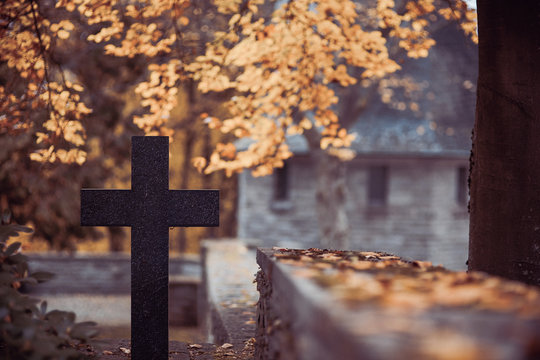  Cemetery with black cross next to cemetery wall in autumn