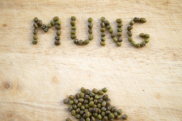 Green gram on wooden cutting board, culinary background with mung beans, small green Asian legume food ingredient