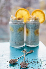 Raw fresh chia seeds in two vintage spoons on the blue wooden table. Healthy chia smoothie  pudding with fresh bananas on the blurred background. Detox superfoods breakfast or dessert. Horizontal