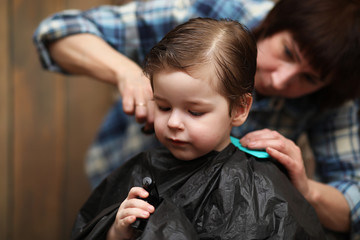 A little boy is trimmed in the hairdresser's bright emotions on 
