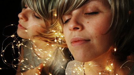 Mujer joven rodeada de luces de navidad reflejándose en un espejo 