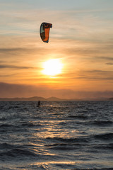 Sunset over the sea or ocean and extreme freestyle sport kitesurfing