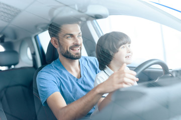 A man with a small son is sitting at the wheel of the car.