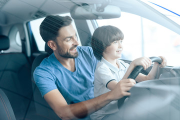 A man with a small son is sitting at the wheel of the car.