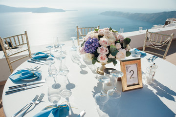 Wedding decor of table on the island of Santorini in gold, blue and white colors at sunset