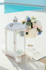 Lantern, candles and bouquet of roses and hydrangea on wedding ceremony on Santorini vertical