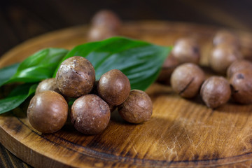 Fresh and ripe macadamiya nuts on the wooden board.