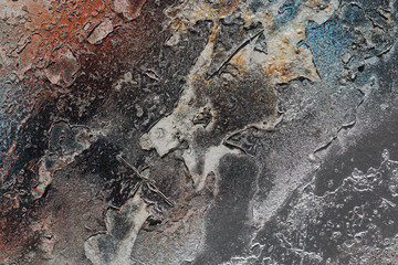 Abstract textured background. Grunge metal close up.
Rusty, dirty old metal sprinkled with orange, blue, brown, grey and silver paint.
Colorful, scratched, cracked and peeled layers. Macro. 