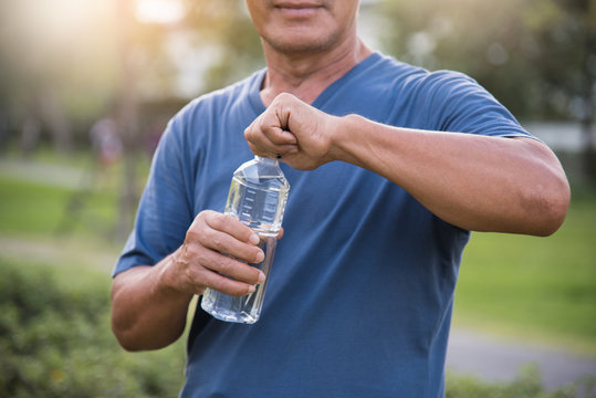 Asian senior male holding bottle of water.