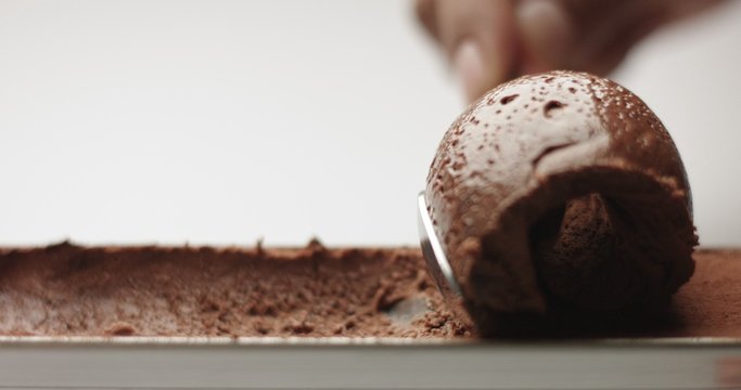 Soft spongy chocolate mousse taken out of a stainless steel pan with a teaspoon isolated on white