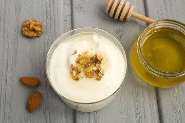Milk yogurt with honey and nuts on the grey wooden background.View from above.