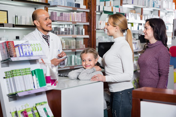 Fototapeta na wymiar Male pharmacist working pharmaceutical store and consulting customers