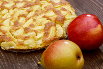 Charlotte of apples and pears on a brown wooden background. Autumn still-life