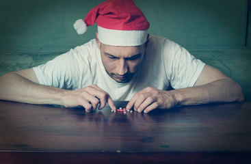 Young man with Santa Claus hat suffering from suicidal depression feeling lonely and sad for New Year and Christmas holiday suicide concept