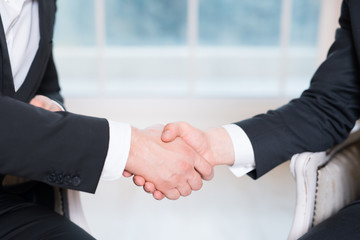 Handshake of two people, businessmen on a light background.