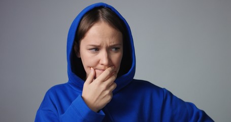 Young woman in large unlabeled bright blue hoodie screams and acts scared and angry showing stress