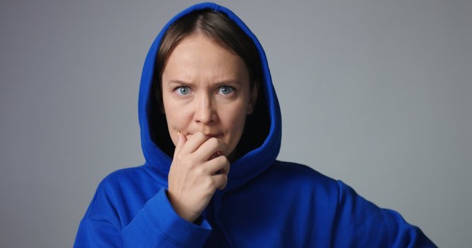 Young woman in large unlabeled bright blue hoodie screams and acts scared and angry showing stress