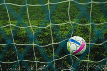 Soccer ball on the green field with net goal