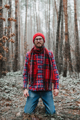a man with a beard in a red cap reacts emotionally in the forest