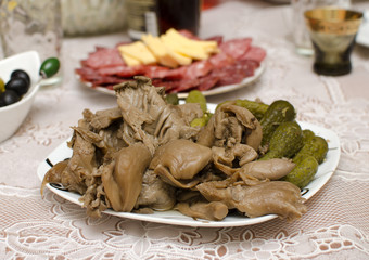 Marinated mushrooms and gherkins on a white plate.