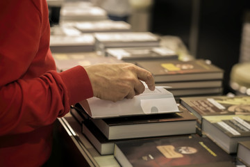 Close-up of hands of elderly person with open book, bookstore, library. Real scene. Education concept, Self-study, reading fiction, pension, interests in elderly, life style
