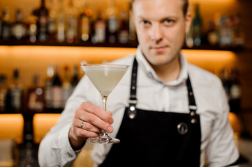 Cocktail glass with fresh alcoholic drink in bartenders hand