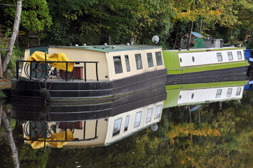 barges converted into houseboats moored on a canal near hebden bridge in yorkshire in woodland
