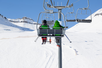 Two skiers on chair-lift and snow ski slope