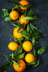 Fresh mandarin with leaves on darl stone background.