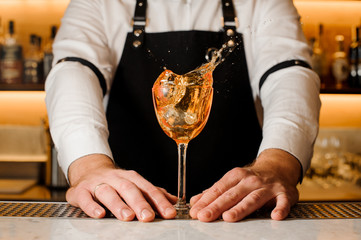 Barman holding a glass with splashing alcoholic drink
