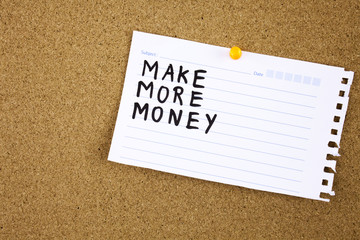 The phrase Make More Money typed on a piece of note paper and pinned to a cork notice board