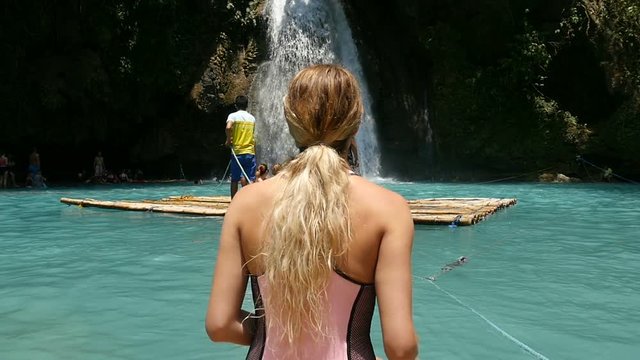 Attractive pretty woman by lagoon pool wearing designer one piece swimsuit