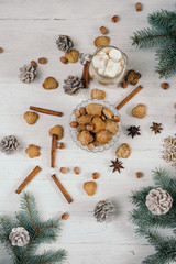 coffee with milk. Biscuits, cinnamon, star anise and Christmas branch spruce with cones, lying on a white wooden table