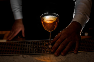 Male hand holding an elegant glass with a light alcoholic drink