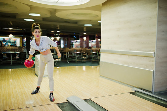 Girl with bowling ball on alley played at bowling club.