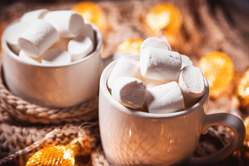 Christmas background with cocoa or coffee with marshmallows in a white cup on a brown knitted...