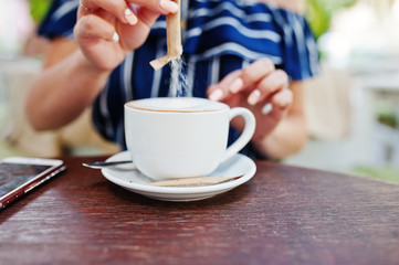 Close up hands with sugar and cup of coffee.
