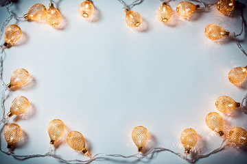 Christmas background with a luminous garland on white. A beautiful holiday idea for postcards and posters. Free space, golden frame
